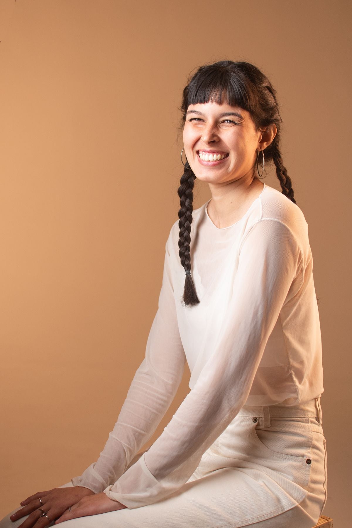 Smiling adult woman with two braids against a warm backdrop — editorial inspiration